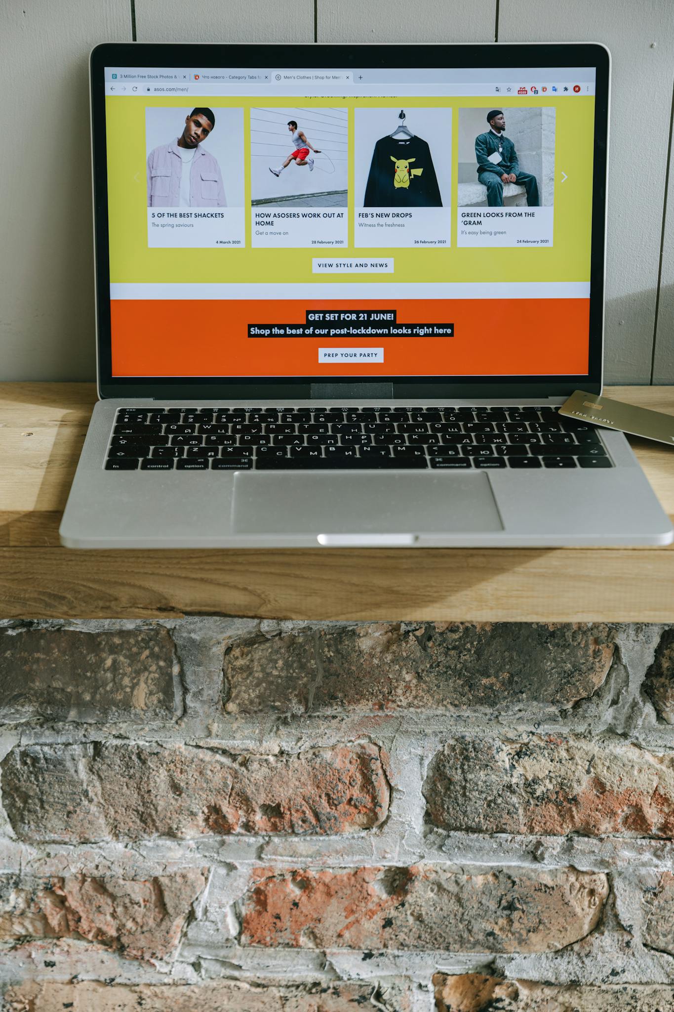 A laptop on a wooden shelf showing a colorful online shopping webpage.
